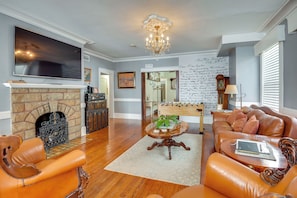 A spacious living room with a fireplace, leather sofas, a flat-screen TV, and a wall with handwritten notes.