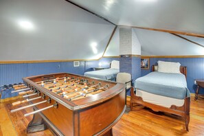 A room with a foosball table, a bed with a patterned bedspread, and a blue wall with a brick accent. - Downtown Daytona Beach Unit: Walk to Halifax River (Daytona Beach)