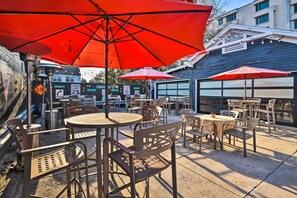 An outdoor patio with tables and chairs, red umbrellas, and a speed limit sign. - Downtown Daytona Beach Unit: Walk to Halifax River (Daytona Beach)