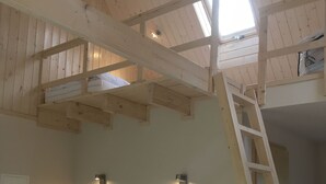 A room with a wooden ceiling, a couch with pillows, a ladder, and two wall-mounted lights. - Semi-detached house FeWo 1 - holiday homes Ohlenbusch (Worpswede)