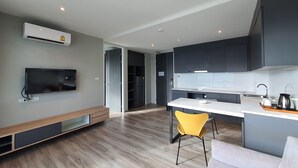 A modern kitchen with grey cabinets, a white countertop, and a yellow chair. - Good Dream Premier (Hat Yai)