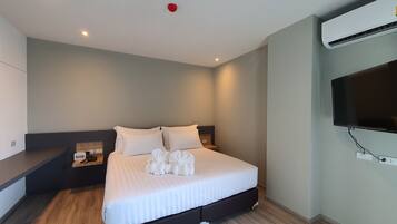 A modern hotel room with a large bed, a flat-screen TV, and an air conditioning unit.