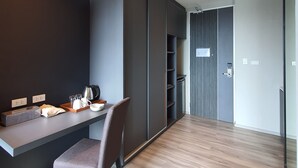 A modern kitchen with a built-in oven, a dining table with chairs, and a dark-colored wall. - Good Dream Premier (Hat Yai)