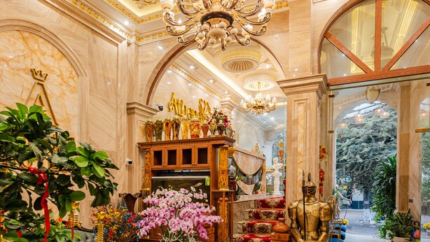 A luxurious interior with ornate gold detailing, a grand chandelier, and a plush seating area. - Athena Hotel (Quy Nhon Nam)