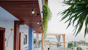 A swimming pool with a tiled edge, a wooden ceiling, and hanging plants. - Athena Hotel (Quy Nhon Nam)