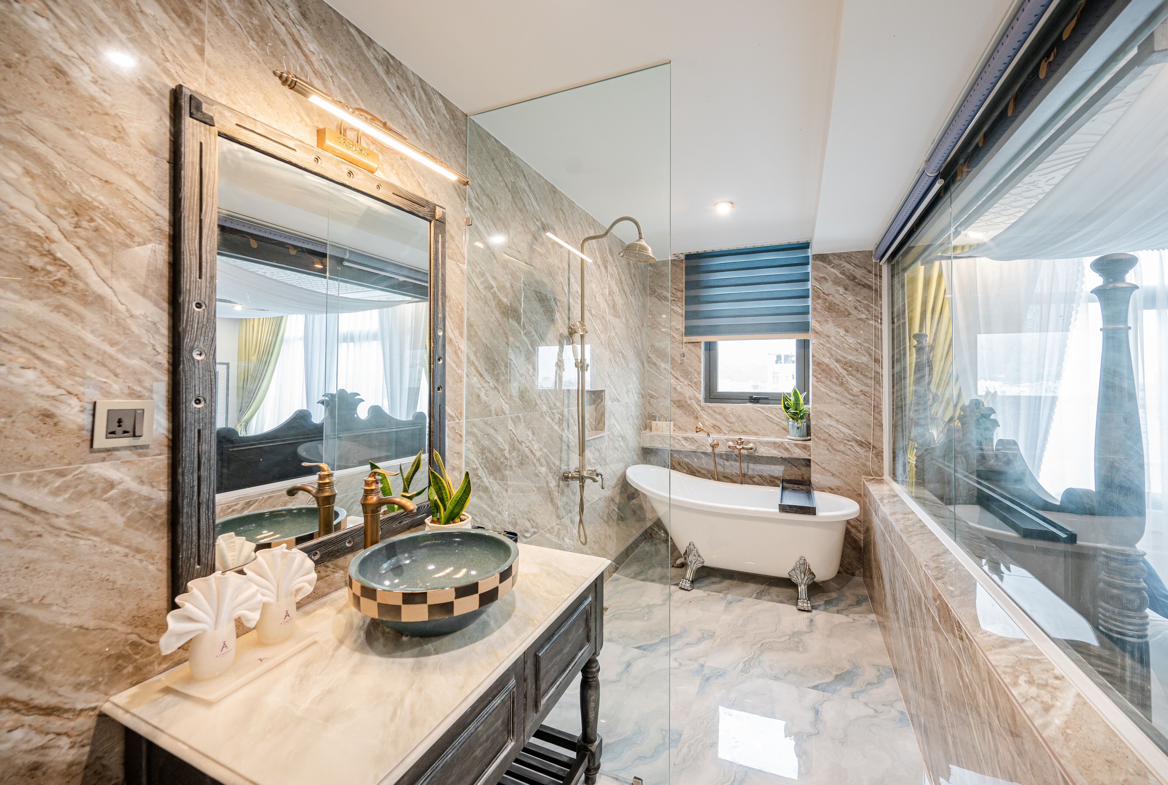 Une salle de bain moderne avec un meuble-lavabo en marbre, une baignoire sur pieds et un grand miroir.