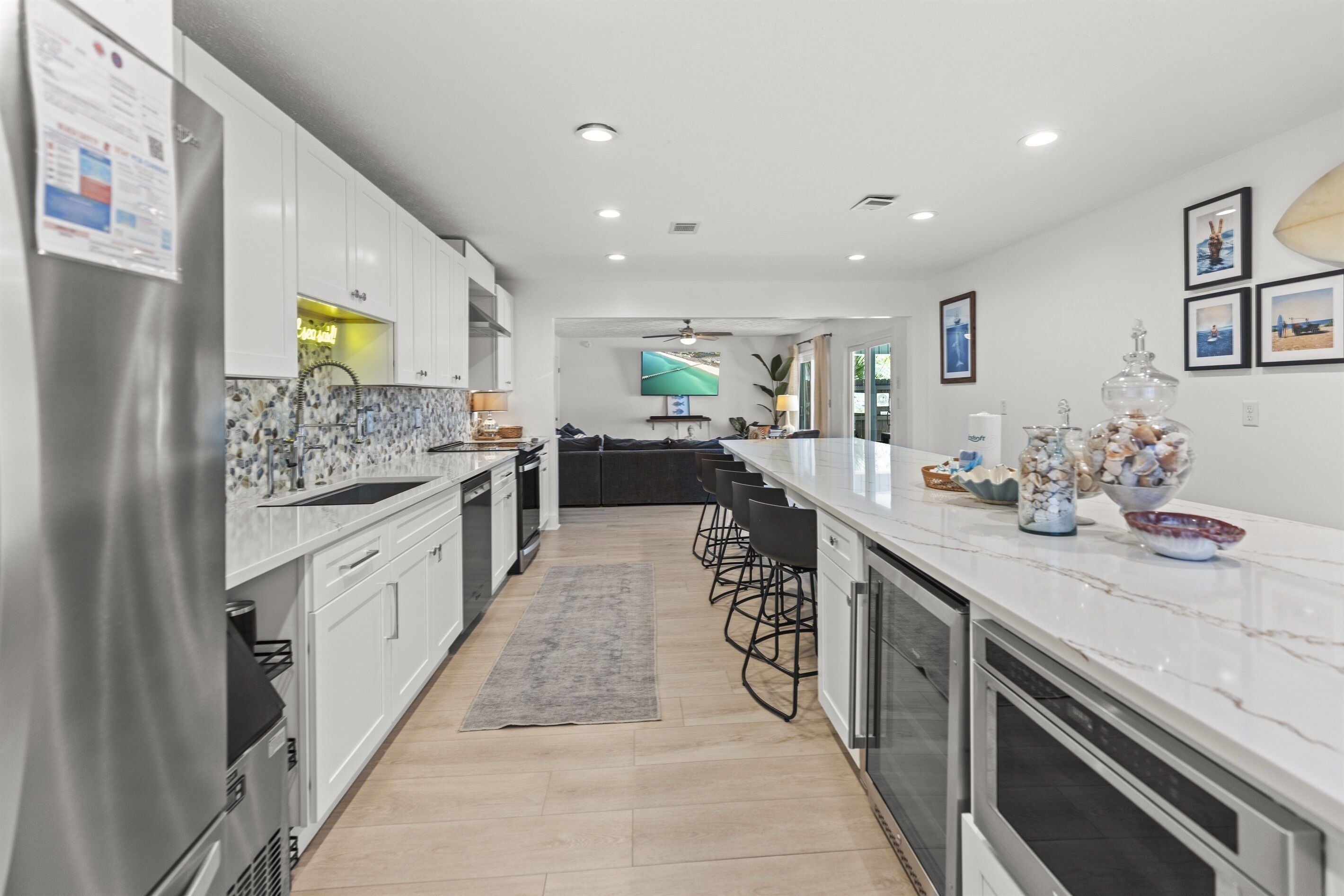 A modern kitchen with white cabinets, a marble countertop, and a central island with bar stools.