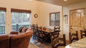 A dining area with a wooden table and chairs, a leather sofa, and a clock on the wall. - Bear Mtn Chalet |Walk 2 Zoo, Bear Mtn & Golf+Games (Big Bear Lake)