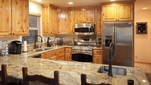A kitchen with wooden cabinets, stainless steel appliances, a granite countertop, and a built-in oven. - Bear Mtn Chalet |Walk 2 Zoo, Bear Mtn & Golf+Games (Big Bear Lake)