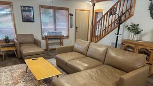 A living room with a sofa, a coffee table, a wooden bench, and a staircase. - KXDJ Riverside 1 on the River (Red River)