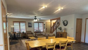 A spacious living area with a dining table, chairs, a sofa, and a staircase. - KXDJ Riverside 1 on the River (Red River)