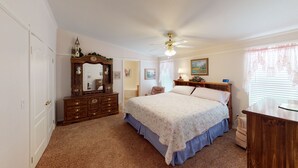 A bedroom with a bed, dresser, vanity, and a ceiling fan. - Jayhawk Cottage - 5 bedroom, in town, WIFI (Red River)