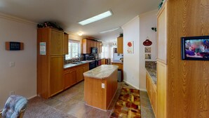 A kitchen with wooden cabinets, a central island, a microwave, and a refrigerator. - Jayhawk Cottage - 5 bedroom, in town, WIFI (Red River)