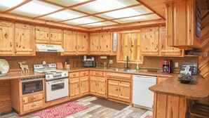 Cucina con mobili in legno, forno, microonde ed elettrodomestici.