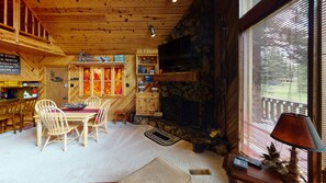 Interior acogedor de una cabaña con comedor, chimenea y pared de piedra.