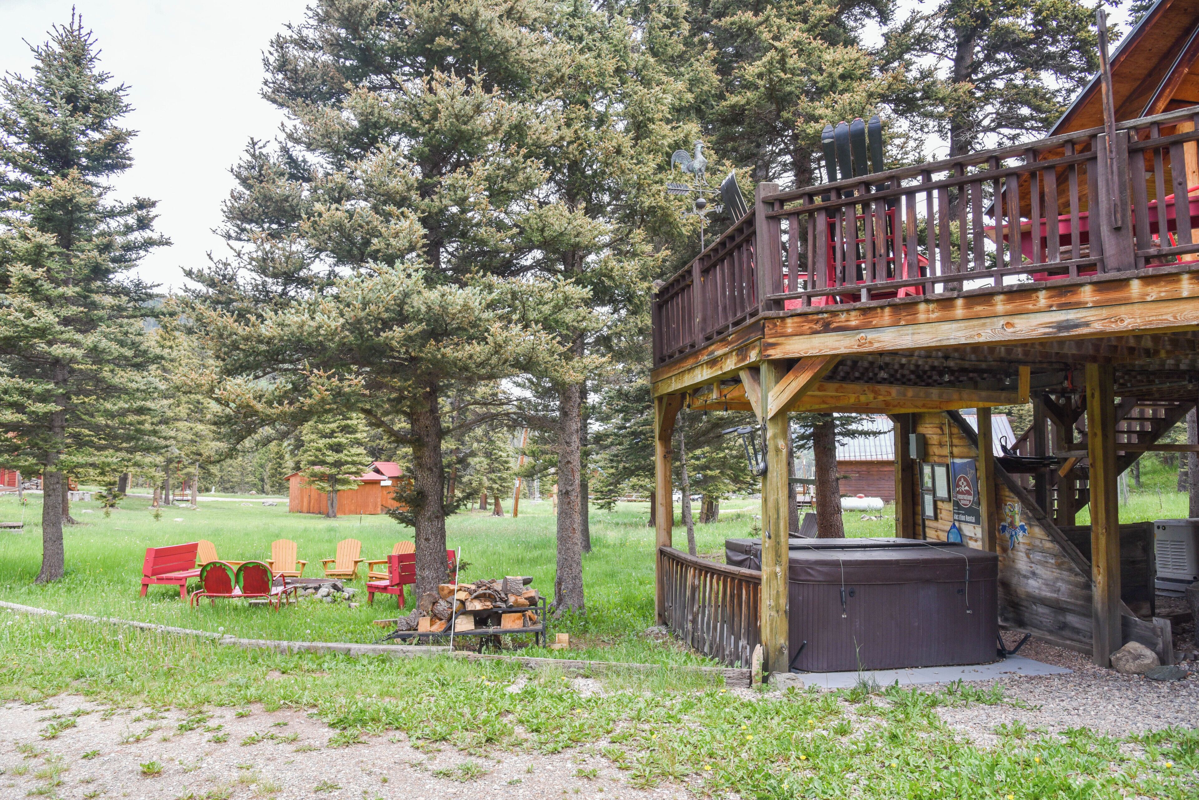 A wooden deck with a hot tub, outdoor seating, and a view of a forested area.