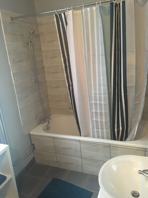 Een bad/douchecombinatie, handdoeken, toiletpapier