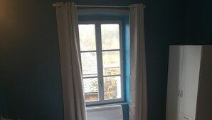 A bedroom with a bed, a wardrobe, and a window with curtains.
