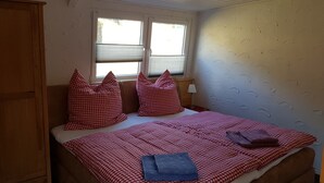 Ein Schlafzimmer mit Bett, Kissen, einem Fenster und einem Nachttisch.