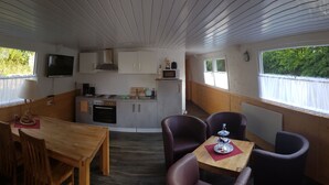 Eine kompakte Küche mit Essbereich, Holzschränken, einer Mikrowelle und einem Fernseher.