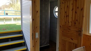 Ein Holzinnenraum mit einer Treppe, die zu einem Balkon führt, einem kleinen Fenster und einer T ür.