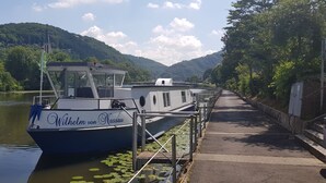 Ein Boot liegt an einem Flussufersteg vor der Kulisse eines Schlosses.