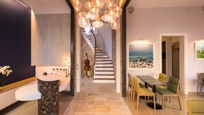 A modern interior with a stone staircase, a dining area with chairs, and a large window with a view. - Acanthus blue (Corfu)