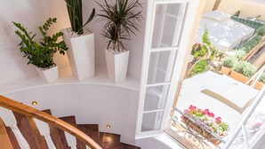 A spiral staircase with white balusters and wooden steps, leading to a balcony with potted plants and flowers. - Acanthus blue (Corfu)