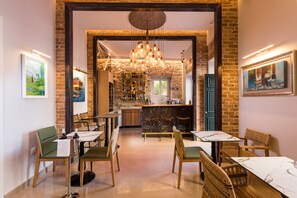 Un restaurante con pared de ladrillo, una zona de bar y un espacio de comedor con mesas y sillas.