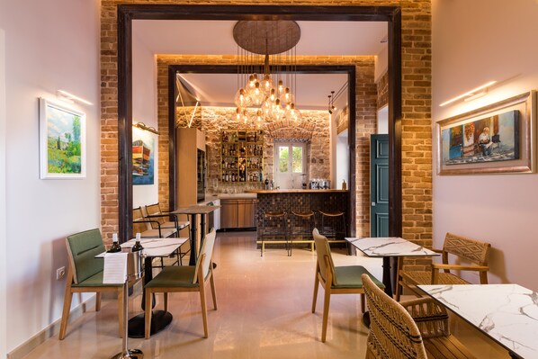 Un restaurante con pared de ladrillo, una zona de bar y un espacio de comedor con mesas y sillas.