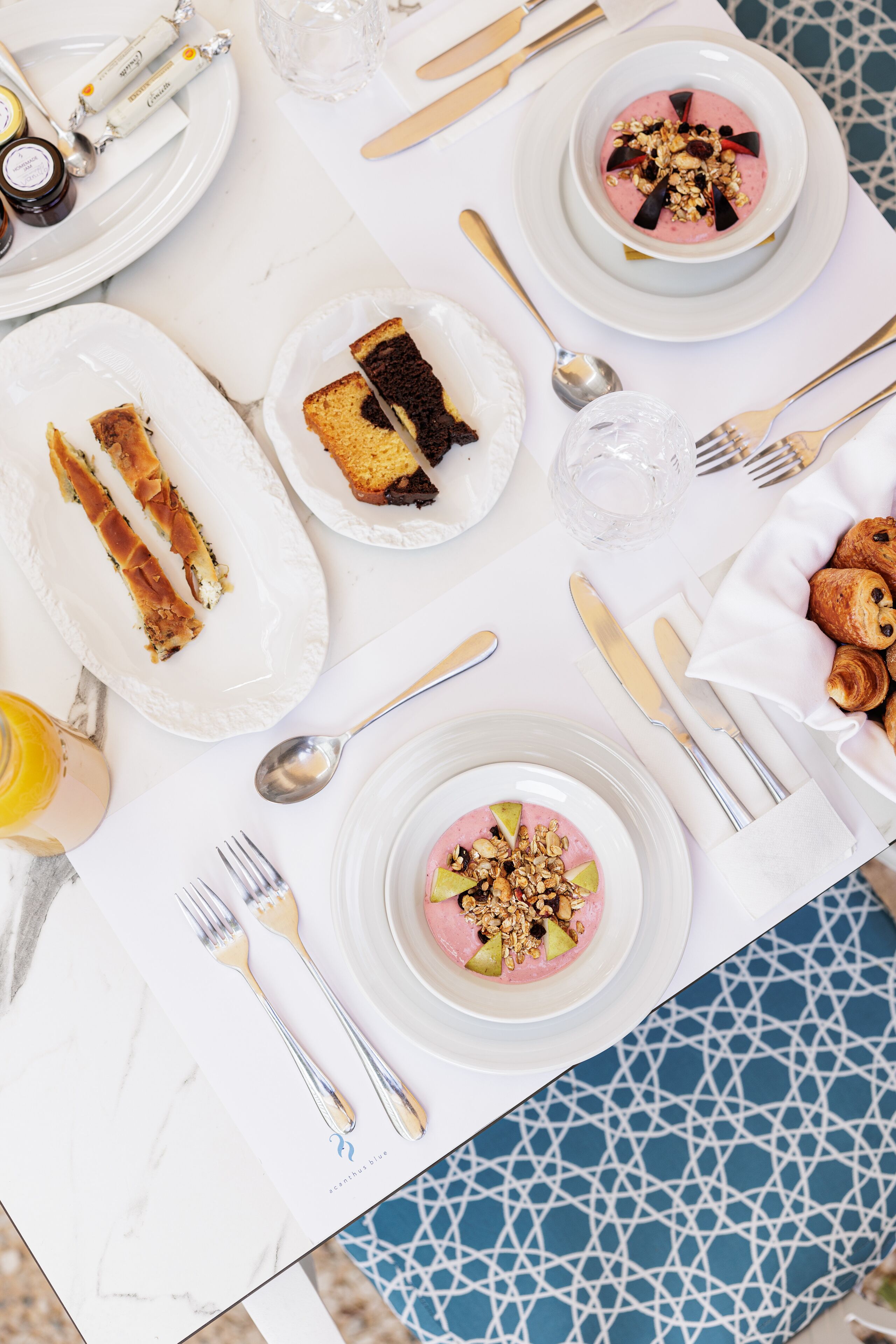 A table set for breakfast with plates of food, cutlery, and a glass of water.