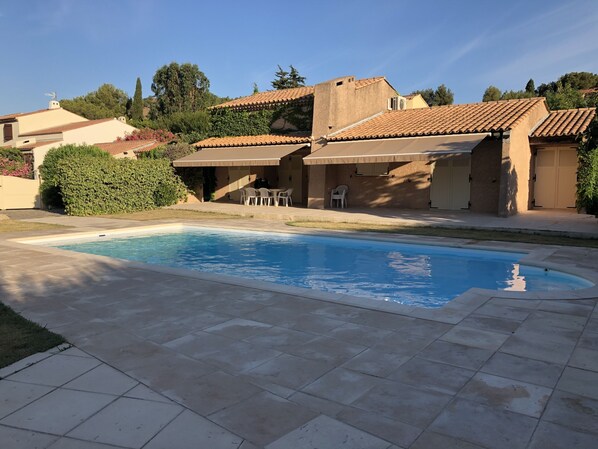 A swimming pool with tiled deck, outdoor seating, and a covered patio area. - Villa with a private pool and fenced-in yard, a 10-minute walk from the beach (Bormes-les-Mimosas)