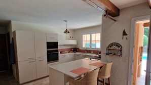 Una cocina amplia con una isla grande, armarios blancos y una viga de techo de madera.
