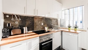 Een moderne keuken met witte kastjes, een zwart aanrecht en een vaatwasser.