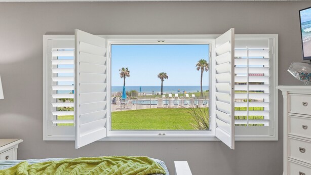 A bedroom with a large window, a bed, a dresser, and a TV. - ✨Direct Ocean - Chateau by the Sea 13C✨ (New Smyrna Beach)