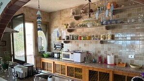 Eine Küche mit Granit Arbeitsplatte, einer Mikrowelle, einem Toaster und verschiedenen Küchenutensilien. Ein Fenster sorgt für natürliches Licht und bietet einen Blick ins Freie.