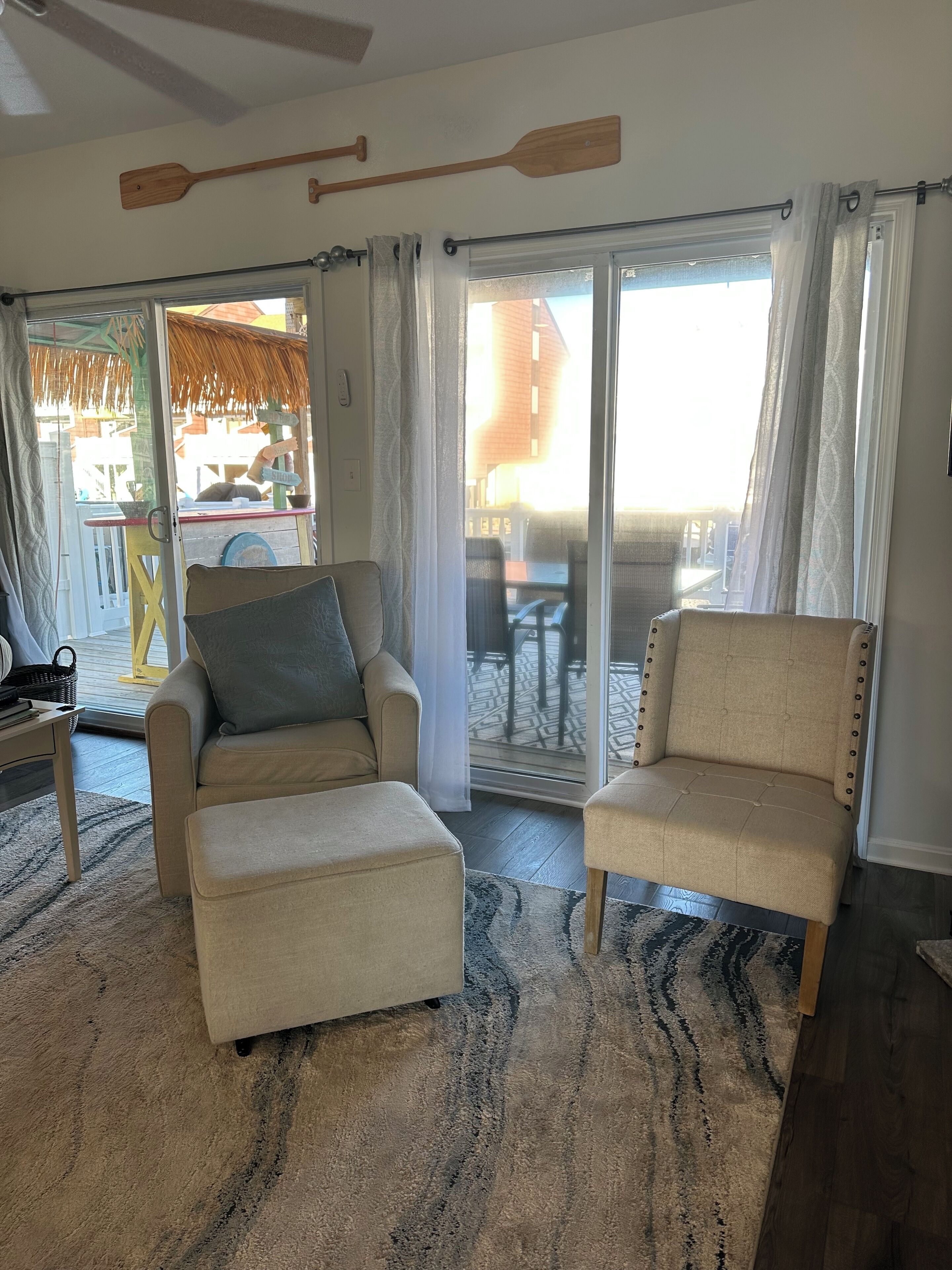 A living room with two beige armchairs, a small table, and a patterned rug.