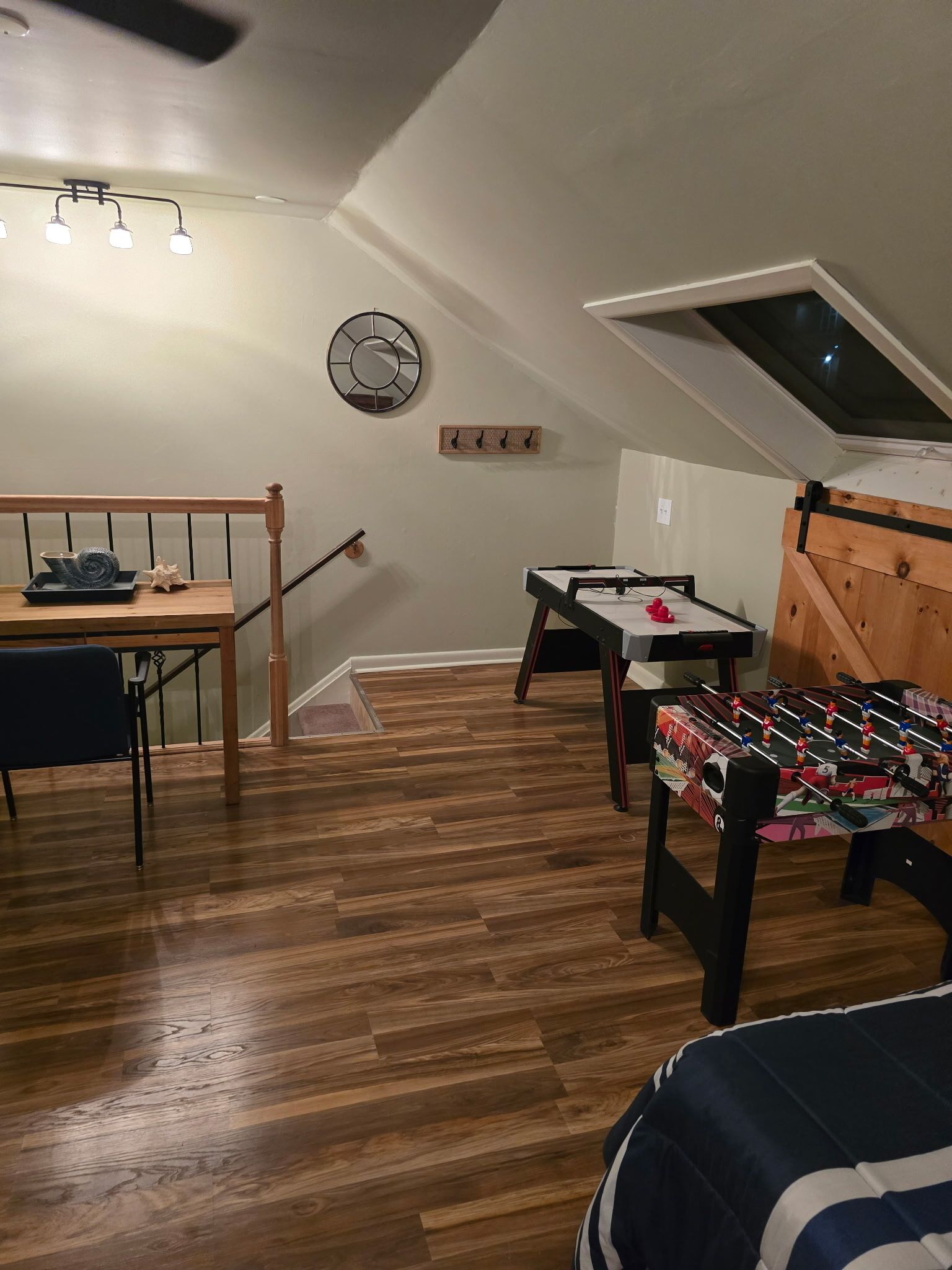 Habitación compacta con mesa de comedor, mesa de futbolín, un pequeño sofá y ventilador de techo.