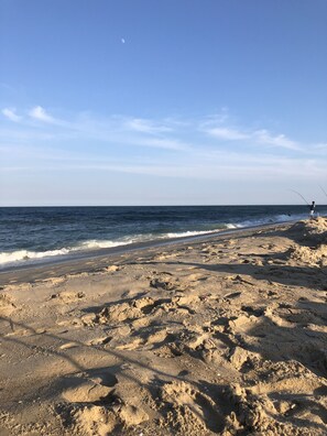 A sandy beach with a clear sky and calm sea.