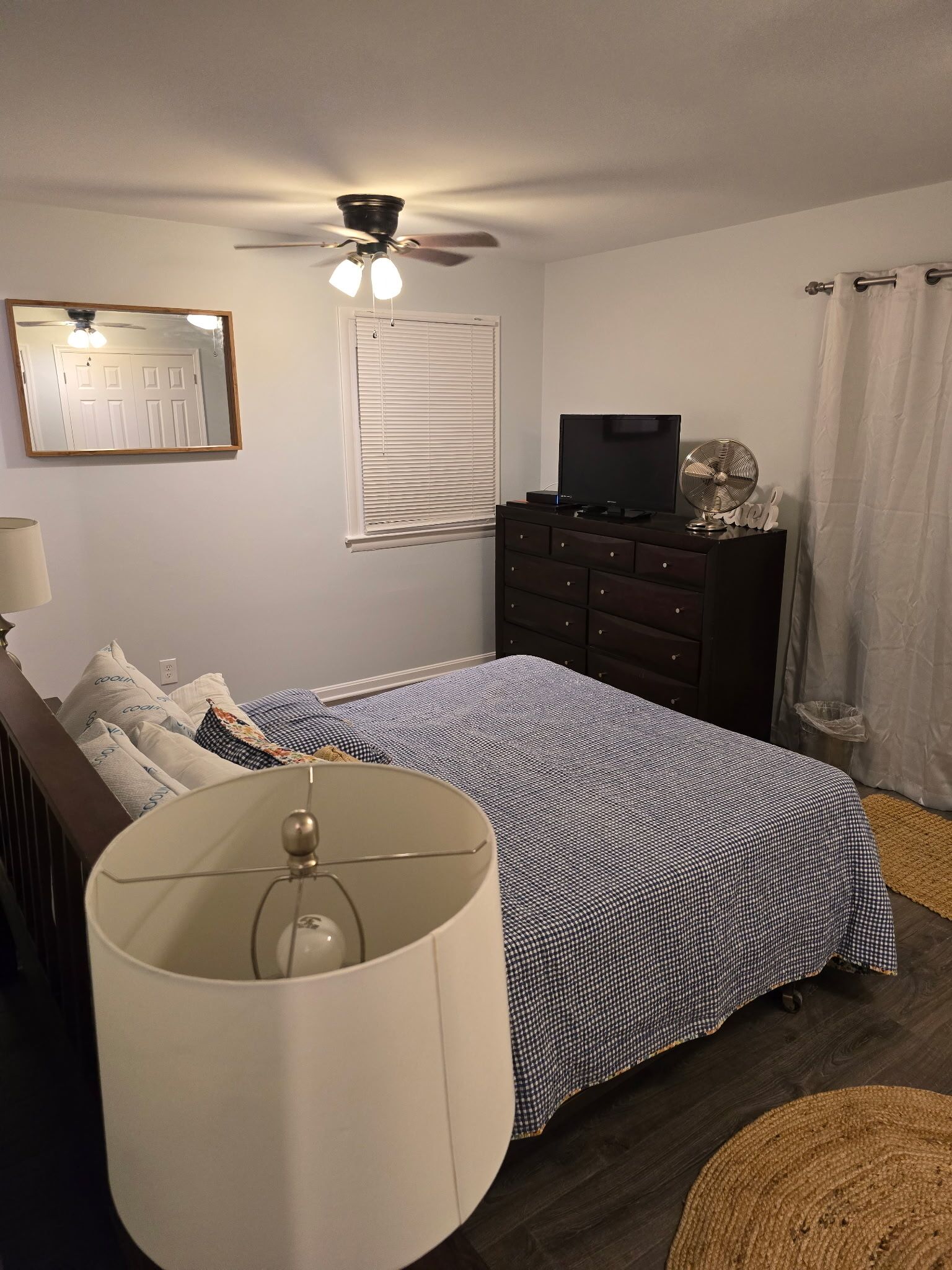 Ein Schlafzimmer mit Bett, Kommode, Deckenventilator und Fernseher.