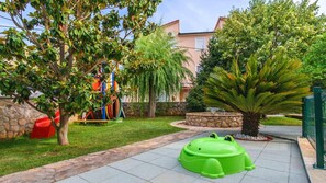 Explore a lush outdoor space surrounded by greenery and play structures for kids.