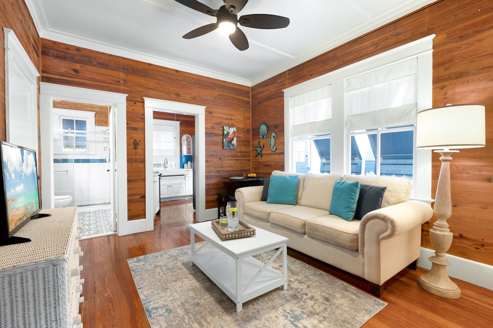 A living room with a beige sofa, white coffee table, and a ceiling fan.