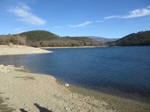 Ein ruhiger See mit einem Sandstrand und Hügeln im Hintergrund.
