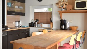 Eine moderne Küche mit einem Holztisch, Stühlen und einer Uhr an der Wand.