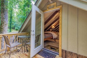 Eine Holzhütte mit Glastür, die zu einem Schlafzimmer mit Bett und Lampe führt.