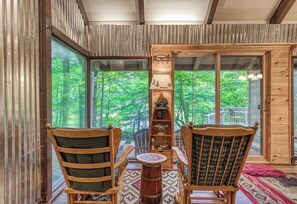 A cozy room with wooden furniture, a drum table, and a lamp with a forest scene. - Creekside | Hot Tub | Wood Burning Fireplace | Fire Pit | Wifi (Gatlinburg)