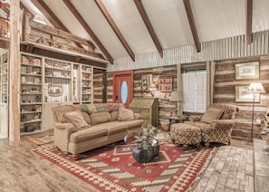 A cozy living room with a wooden ceiling, a red door, and a fireplace. There are two sofas and a coffee table. - Creekside | Hot Tub | Wood Burning Fireplace | Fire Pit | Wifi (Gatlinburg)