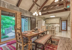 A dining area with a wooden table set for four, a bench, and a view of the outdoors. - Creekside | Hot Tub | Wood Burning Fireplace | Fire Pit | Wifi (Gatlinburg)