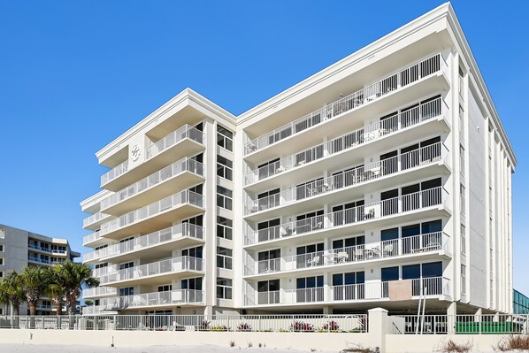 A multi-story hotel with balconies, a flat facade, and a clear blue sky.