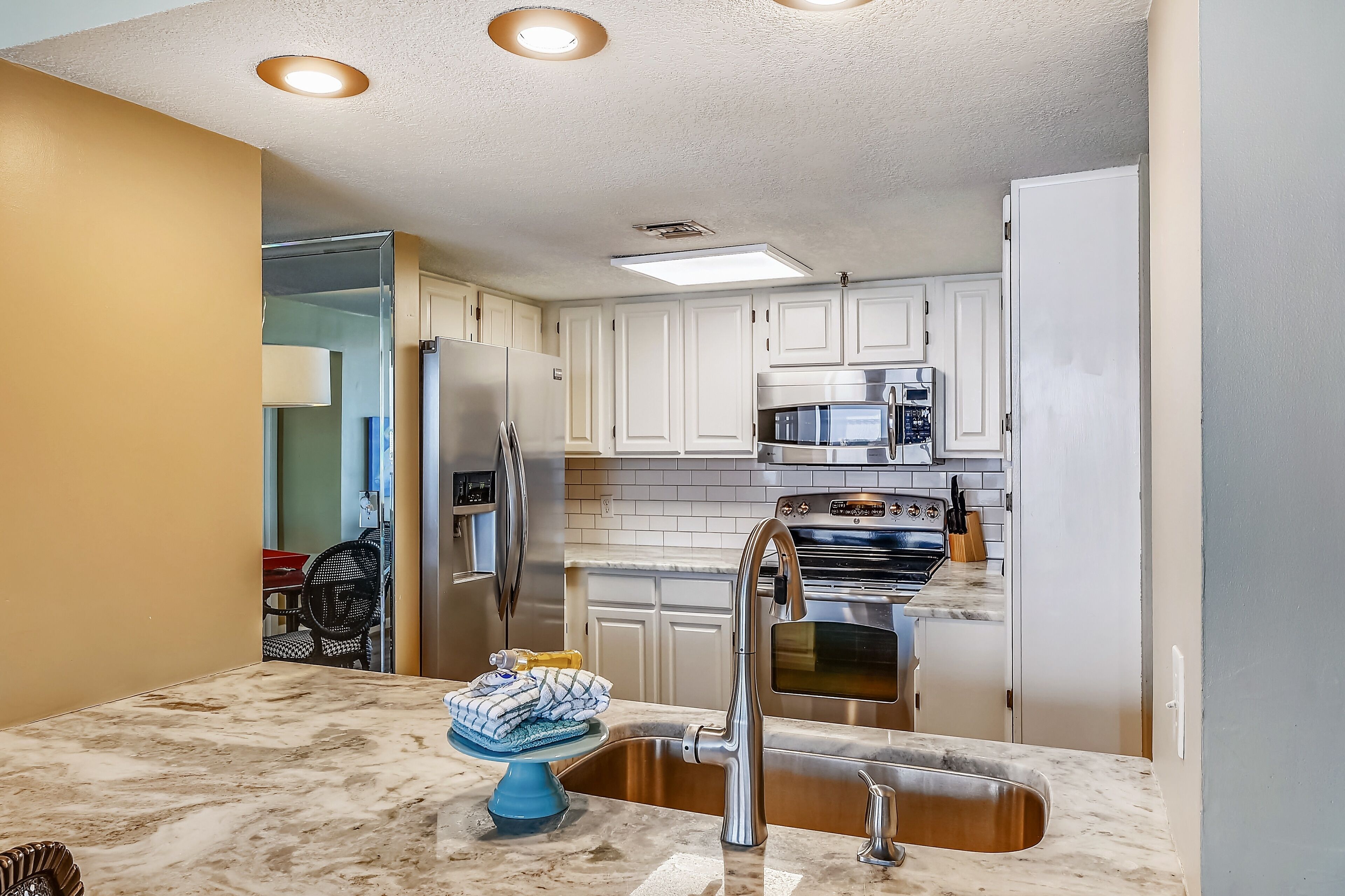A modern kitchen with white cabinets, stainless steel appliances, and a marble countertop.